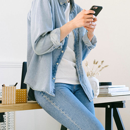 Busy, standing up, leaning against desk checking phone