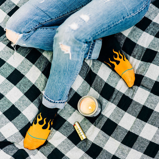 Overhead view of someone sitting on picnic wearing flame socks with a candle lit.