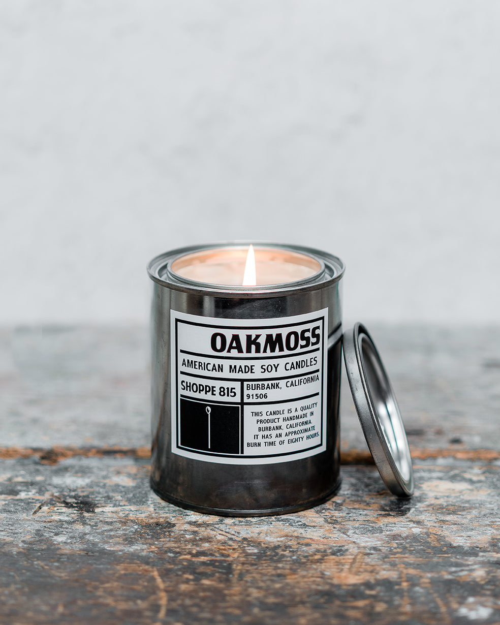 Lit Oakmoss gender neutral tin candle on wooden shelf