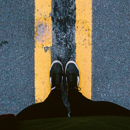 Standing on the double yellow on the road.  Wearing black high top Vans and having a Scents of Adventure
