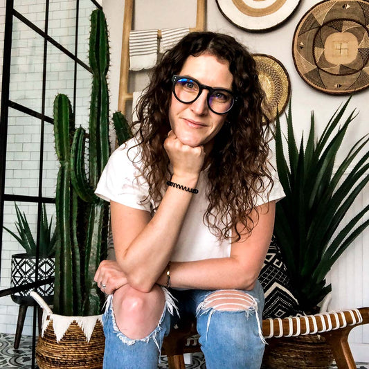Katy smiling wearing caddis glasses, white tshirt, jeans in front of cactus