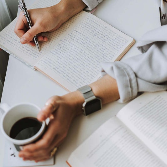 Writing in a journal with a coffee in hand.