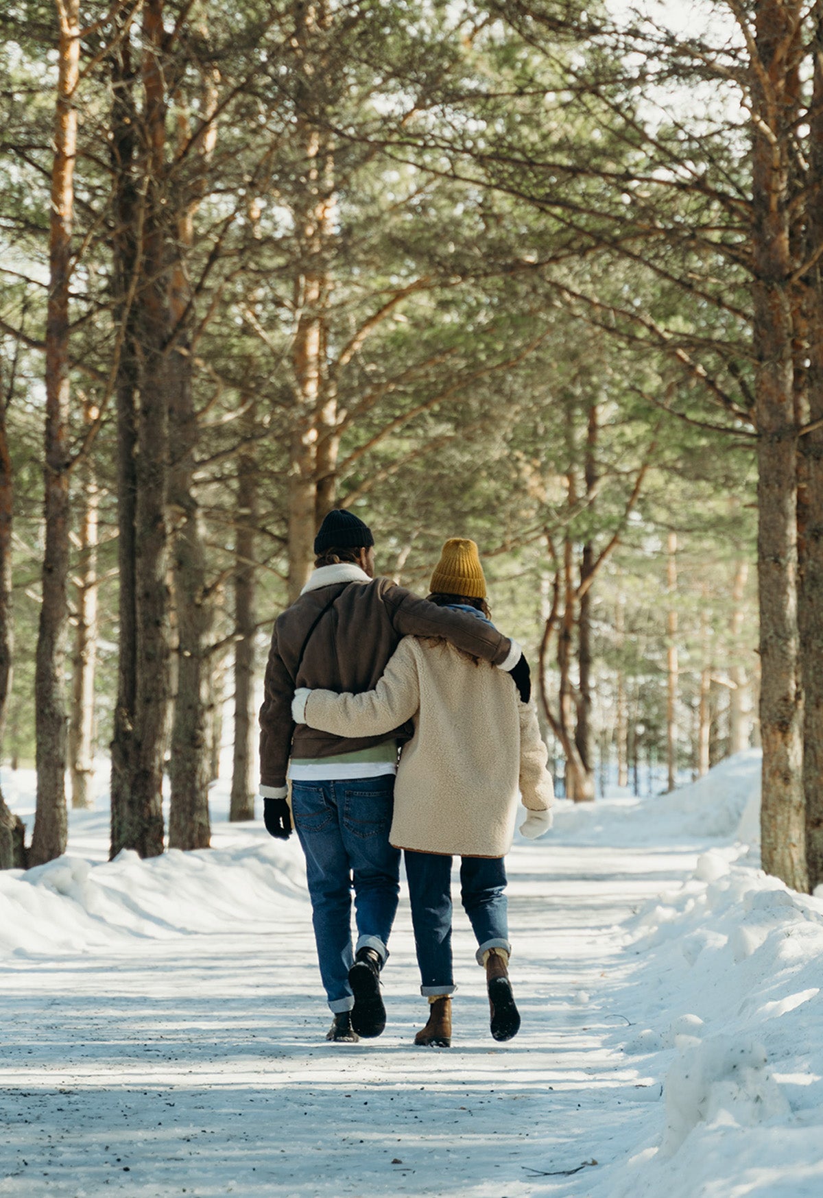 A couple walking on a snow covered path on a winter day, enjoying the smell of spruce trees.  A simple moment that will ignite memories for years to come! 