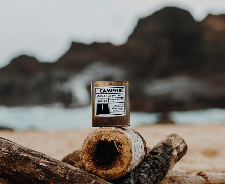Campfire candle on a log with a sandy beach background 