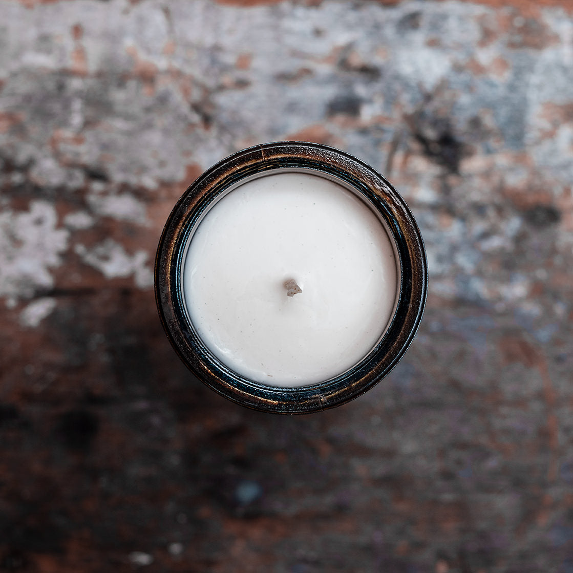 Overhead view of amber glass candle on wooden shelf