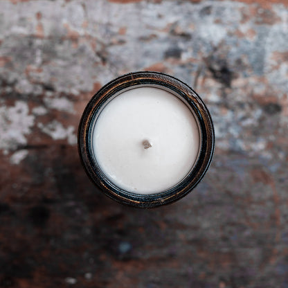 Overhead view of amber glass candle on wooden shelf
