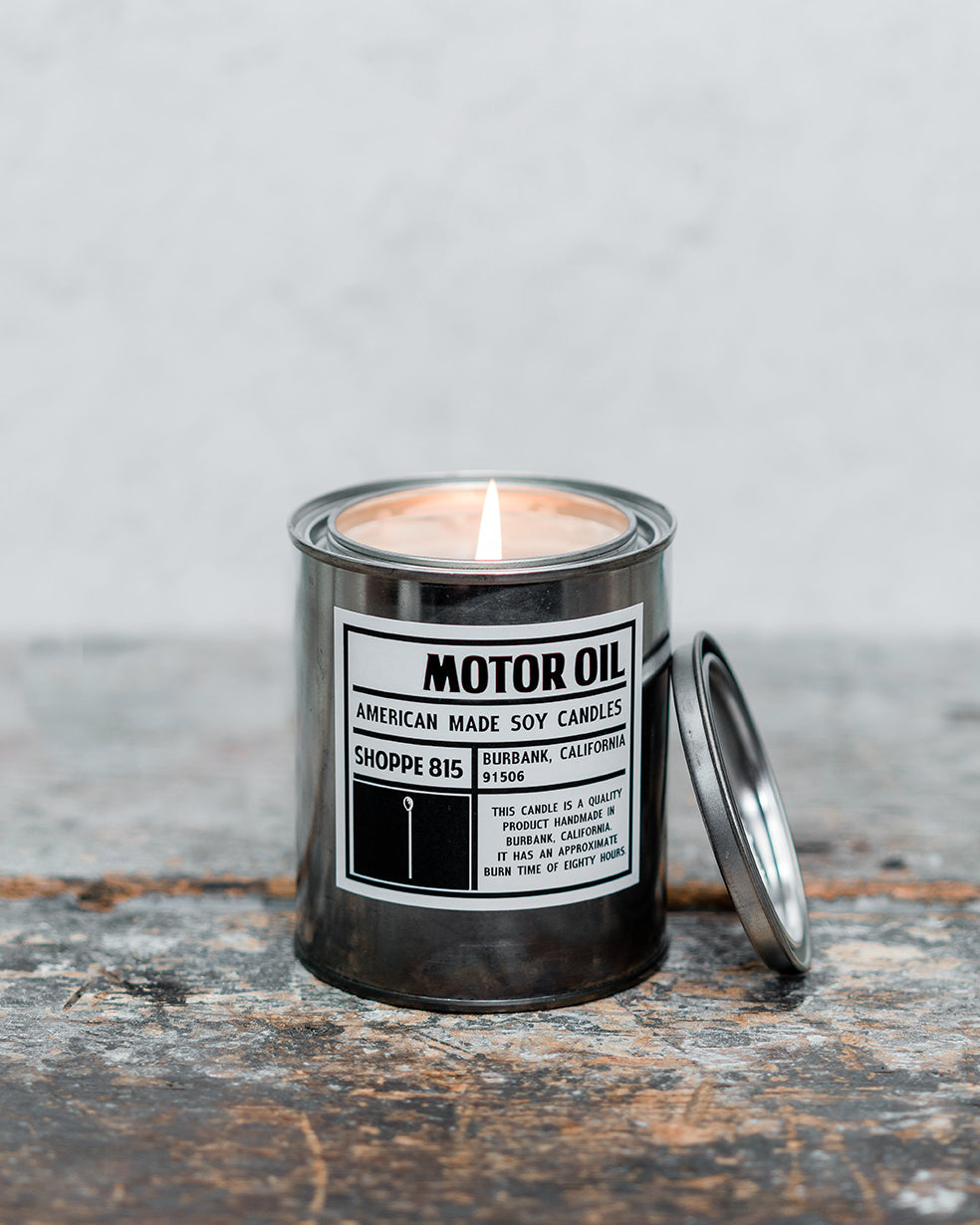 Lit Motor Oil gender neutral tin candle on wooden shelf