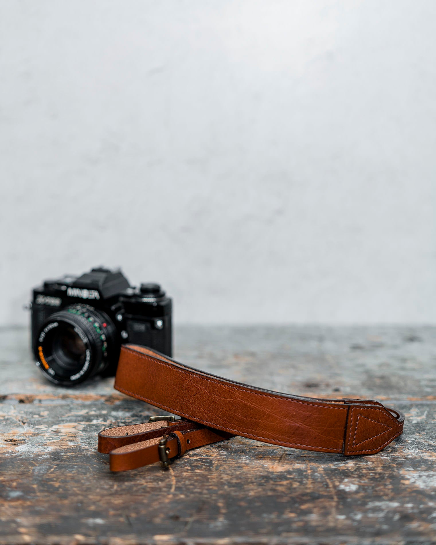 Leather camera strap on table with camera in background