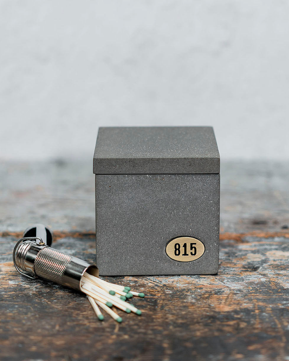 Concrete square candle with lid sitting on table with matches