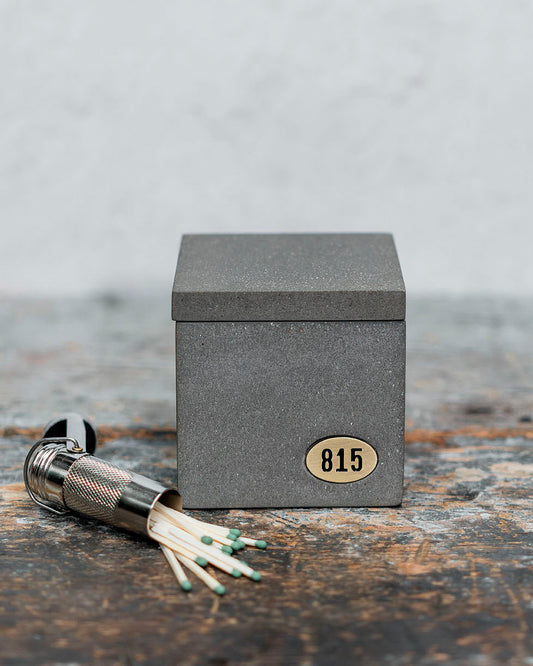 Concrete square candle with lid sitting on table with matches