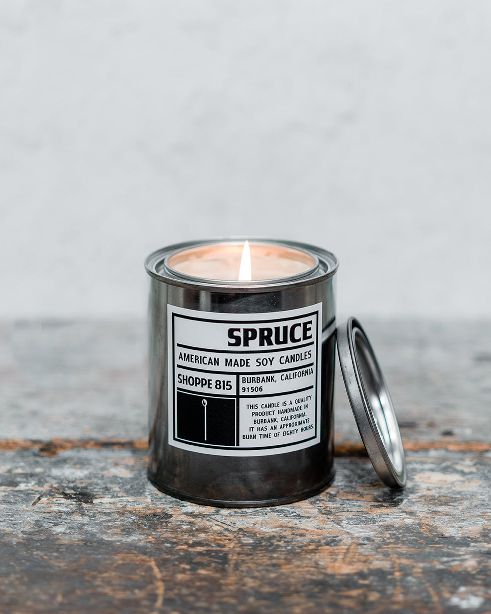 Lit Spruce gender neutral tin candle on wooden shelf