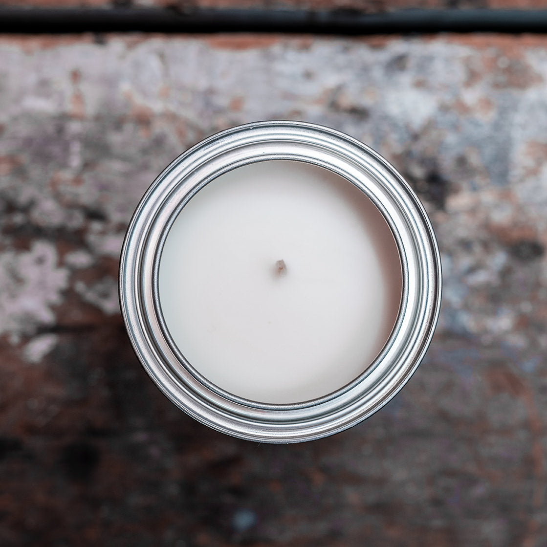 Overhead view of gender neutral tin candle on wooden shelf