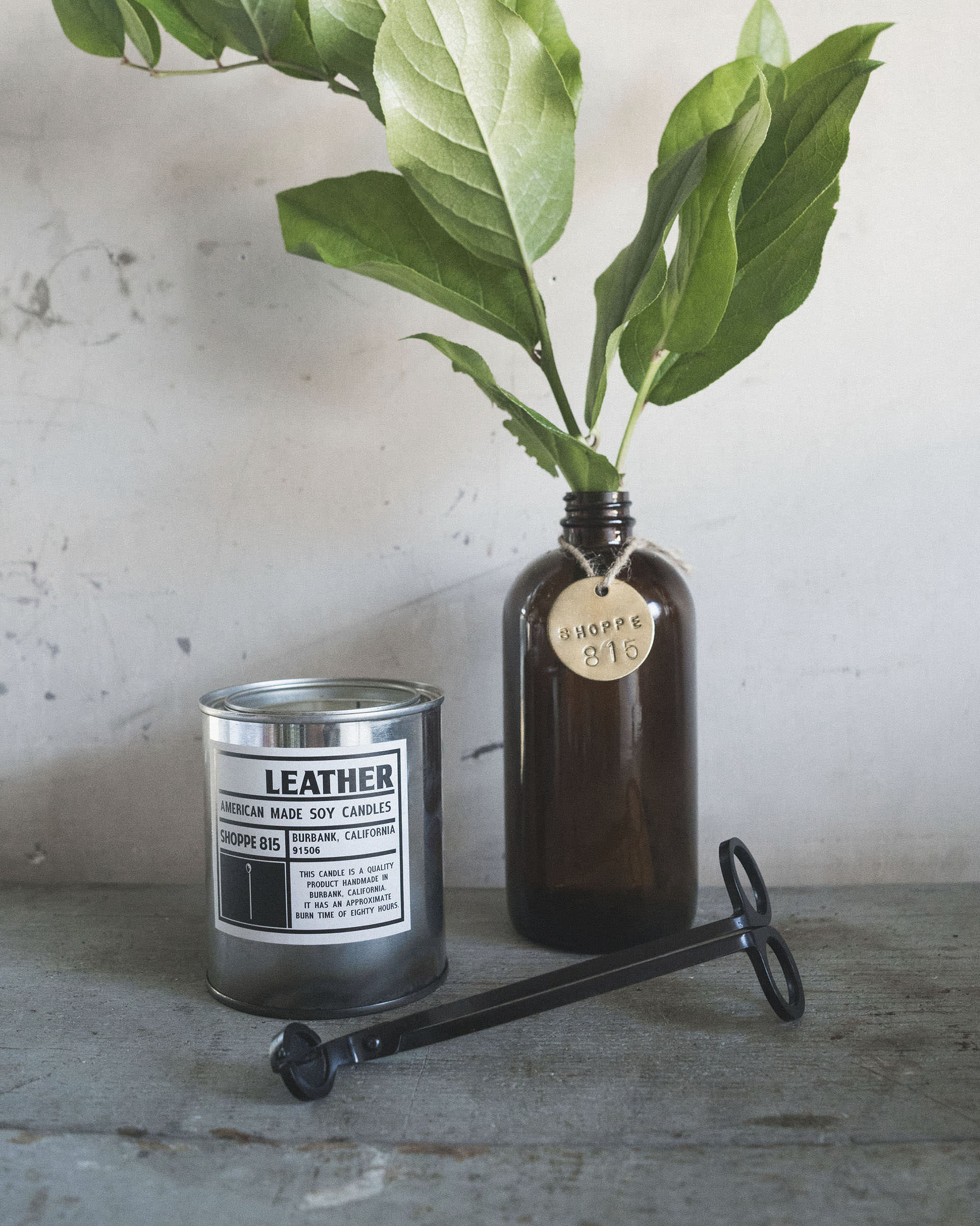 Matte Black wick trimmer on counter with leather candle and plant